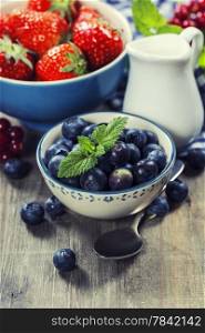 Berries in bowls on Wooden Background. Strawberries, Raspberries and Blueberries. Health, Diet, Gardening, Harvest Concept