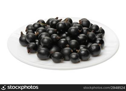 Berries of a black currant on a white plate on a white background, isolated