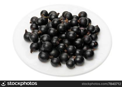Berries of a black currant on a white plate on a white background, isolated