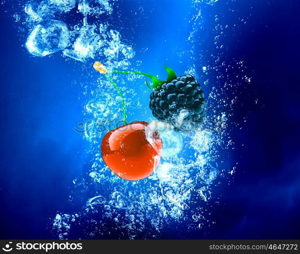 Berries sink in water. Fresh berries in clear blue crystal water