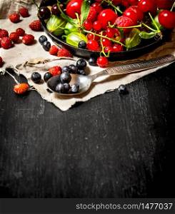 Berries with spoon on cloth. On a black wooden background.. Berries with spoon on cloth.