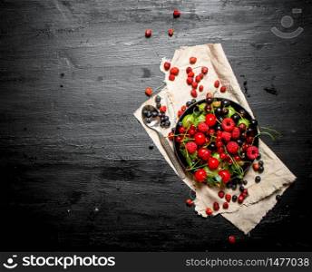 Berries with spoon on cloth. On a black wooden background.. Berries with spoon on cloth.