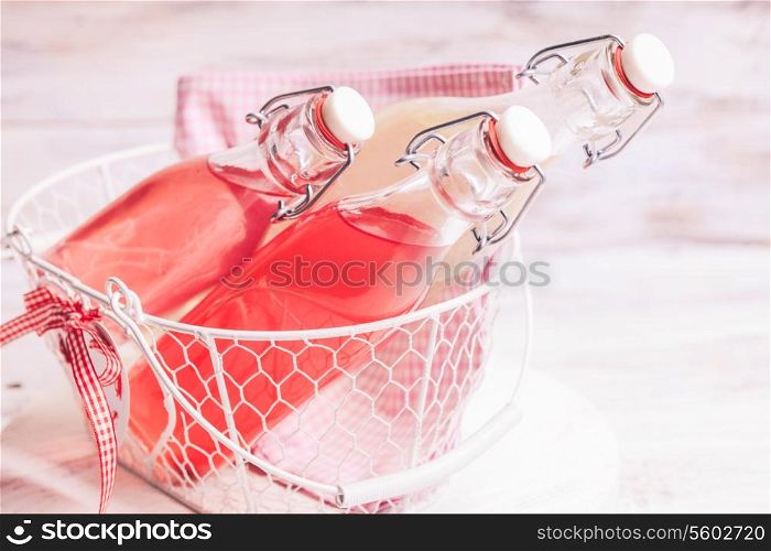 Berry lemonade in the bottles in basket on the grass