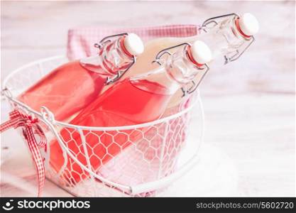 Berry lemonade in the bottles in basket on the grass