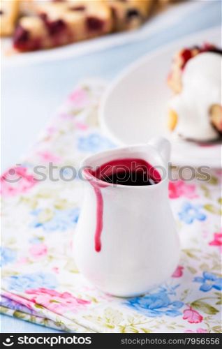 Berry sauce in white milk jug, selective focus