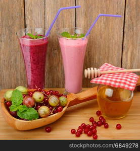 berry smoothie, currants, gooseberries and honey on a wooden surface