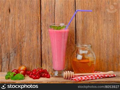berry smoothie, currants, gooseberries and honey on a wooden surface