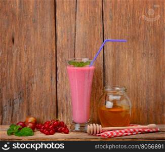berry smoothie, currants, gooseberries and honey on a wooden surface