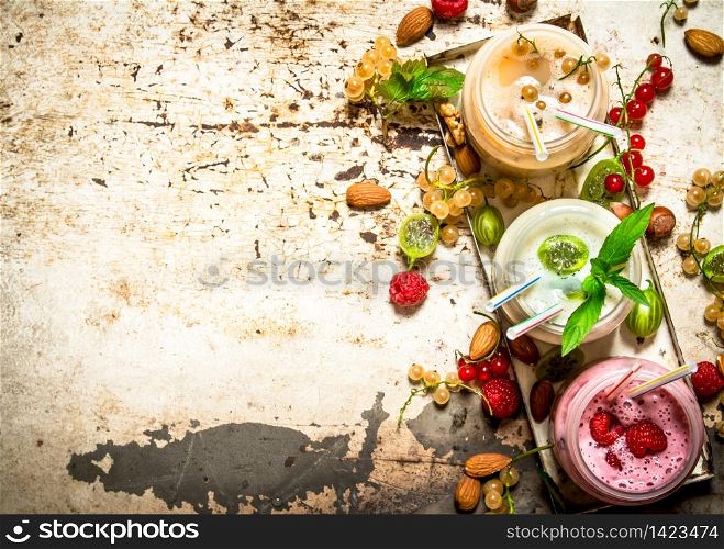 Berry smoothie made from currants, gooseberries and raspberries with nuts. On rustic background.. Berry smoothie made from currants, gooseberries and raspberries with nuts.