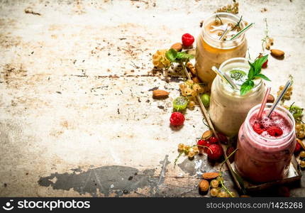 Berry smoothie made from currants, gooseberries and raspberries with nuts. On rustic background.. Berry smoothie made from currants, gooseberries and raspberries with nuts.