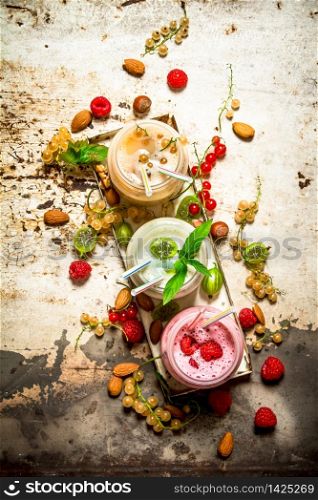 Berry smoothie made from currants, gooseberries and raspberries with nuts. On rustic background.. Berry smoothie made from currants, gooseberries and raspberries with nuts.