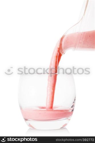 Berry smoothie or yogurt pouring from a jug into a glass isolated on white background. Berry smoothie or yogurt pouring from jug into glass