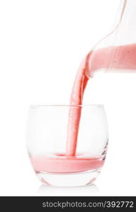 Berry smoothie or yogurt pouring from a jug into a glass isolated on white background. Berry smoothie or yogurt pouring from jug into glass