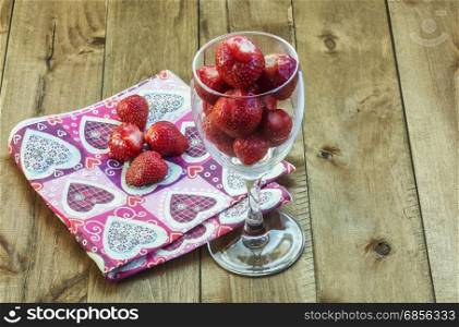 Berry strawberries in a glass fouger on a wooden surface