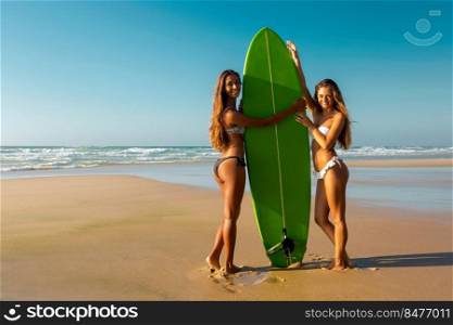 Best friends enjoying the summer, posing with a surfboard on the beach