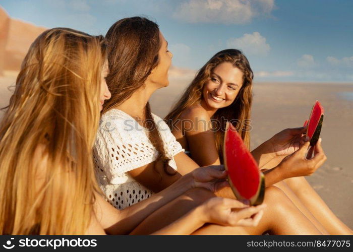 Best friends having fun on the beach and eating watermelon