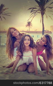 Best friends teen girls having fun on a beach sand at sunset