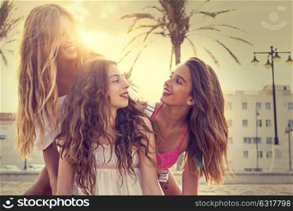 Best friends teen girls having fun on a beach sand at sunset