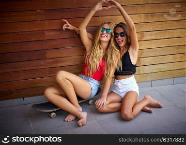 Best friends teen girls on skate heart shape hands fingers smiling having fun
