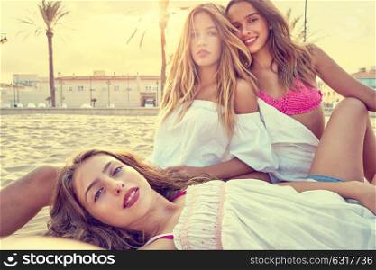 Best friends teen girls together relaxed on a beach sand at sunset