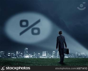 Best interest rate . Businessman standing with back and percent sign in spotlight