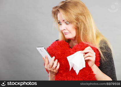 Betrayal, bad relationship, hurt love concept. Shocked heartbroken woman crying and looking at her phone.. Shocked heartbroken woman looking at her phone