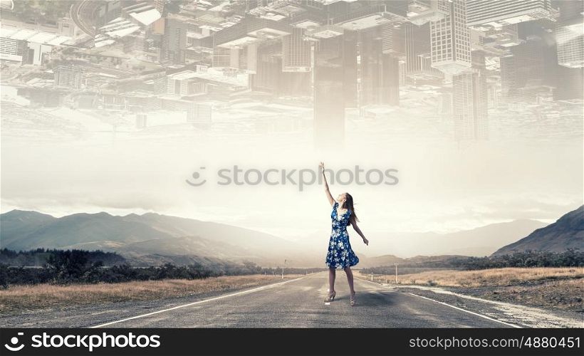 Between two worlds. Young woman in dress on road between two realities