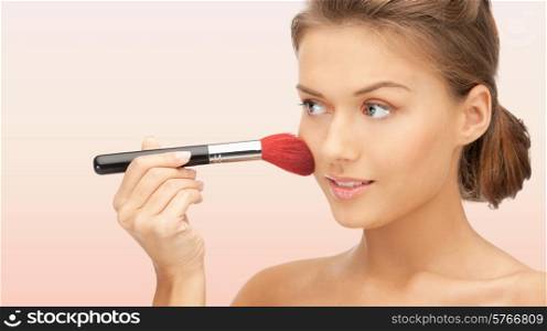 beuty, people and accessories concept - beautiful smiling woman with bare shoulders and make up brush over pink background