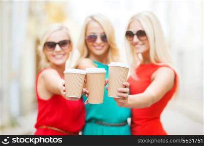 beverage and drink concept - three smiling blonds holding takeaway coffee cups in the city