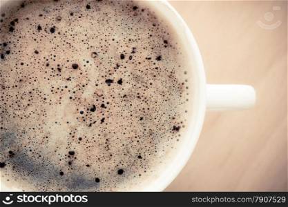 Beverage. Closeup of cup of hot drink coffee cappuccino with froth on wooden table background.