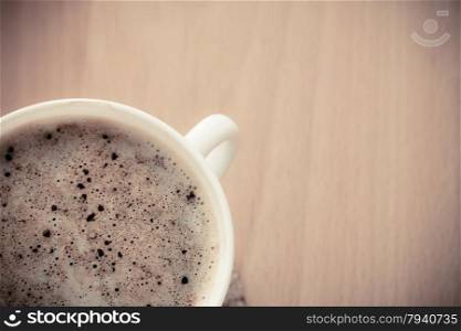 Beverage. Closeup of cup of hot drink coffee cappuccino with froth on wooden table background.