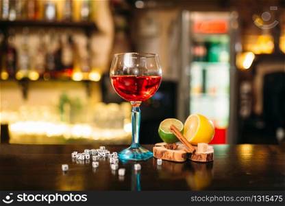 Beverage in glass, lime, lemon, salt and dice on wooden bar counter. Beverage in glass, lime, lemon, salt and dice
