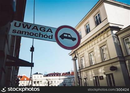 ""Beware of car" in polish language. Attention sign on classic architecture background"