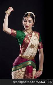 Bharatanatyam dancer flexing muscle over black background