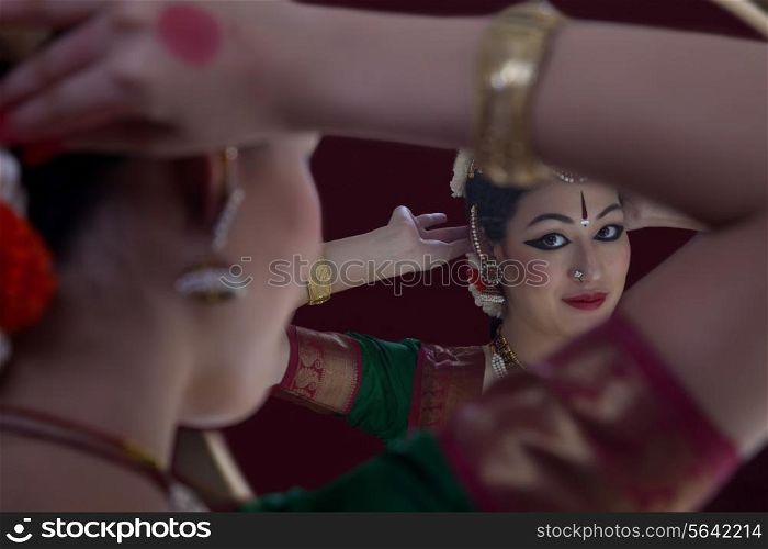 Bharatanatyam dancer getting dressed in front of mirror over black background