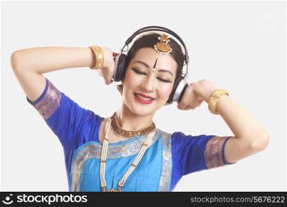 Bharatanatyam dancer listening music on headphones over white background