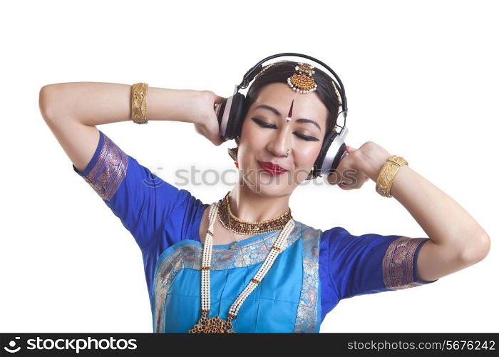 Bharatanatyam dancer listening music through headphones over white background