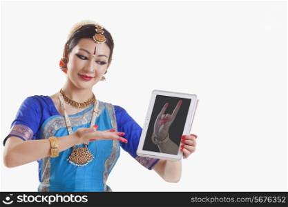 Bharatanatyam dancer showing Simhamukha mudra on digital tablet over white background