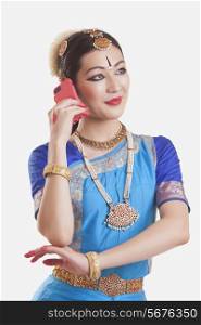 Bharatanatyam dancer using smart phone over white background