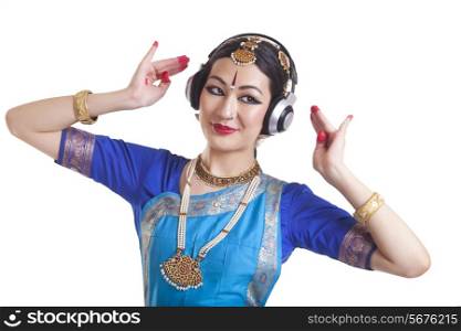 Bharatanatyam dancer wearing headphone while performing over white background