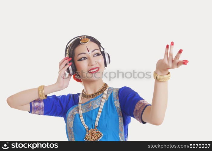 Bharatanatyam dancer wearing headphones while dancing over white background