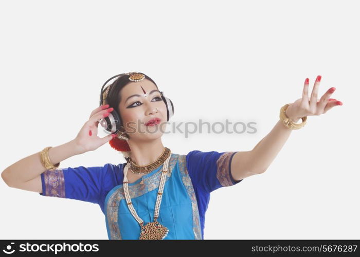 Bharatanatyam dancer wearing headphones while performing over white background