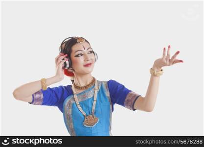 Bharatanatyam dancer wearing headphones while performing over white background