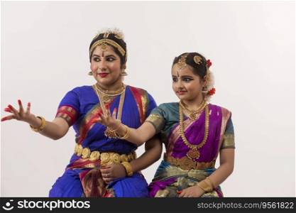 Bharatnatyam dancer and her student performing gracefully through their expressions and hands. 