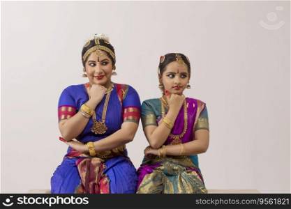 Bharatnatyam dancer and her student performing gracefully through their eyes and expressions. 