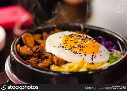 bibimbap in a heated stone bowl , korean style food