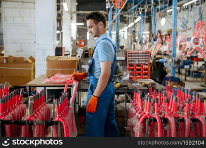 Bicycle factory, worker holds pink kid&rsquo;s bike fork. Male mechanic in uniform installs cycle parts, assembly line in workshop, industrial manufacturing. Bicycle factory, worker holds pink kid&rsquo;s bike fork