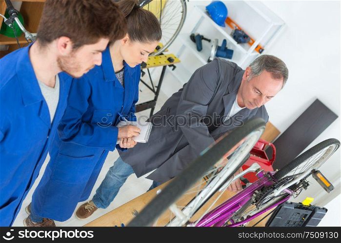 bicycle mechanic and apprentices in workshop