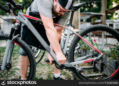 Bicycle mechanic hands adjusts with service tools cycling pedals. Cycle workshop outdoor. Bicycling sport, repairman at work. Bicycle mechanic hands adjusts cycling pedals