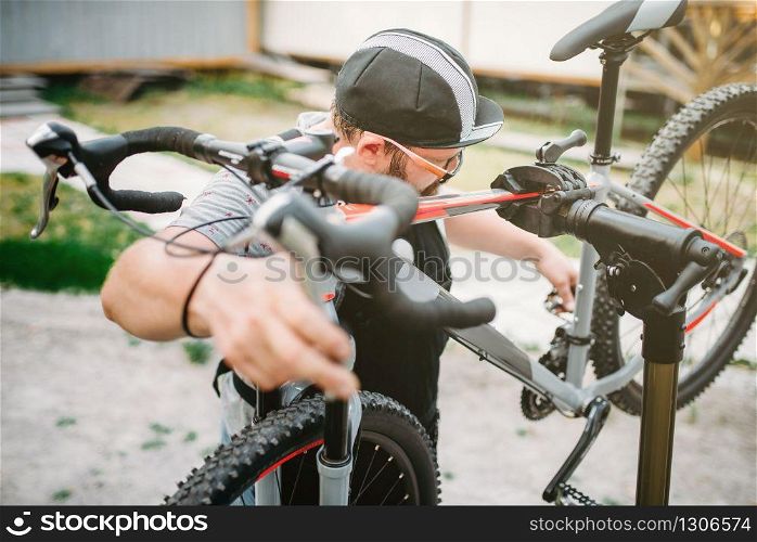 Bicycle mechanic repair bike, top view. Cycle workshop outdoor. Bicycling sport, bearded service man work with wheel